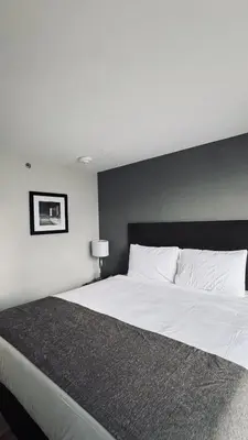 a bedroom with a large white bed with a black headboard at Capital Hotel Long Island City in Queens
