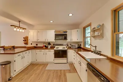 a kitchen with white cabinets and wooden floors at 2 Mi to Elk Mountain Poconos Escape on 11 Acres! in Pleasant Mount