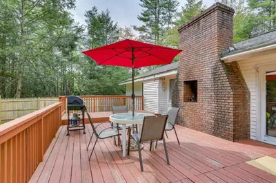 a patio with a table and a red umbrella at Charming Swan Lake Apartment with Deck! in Swan Lake