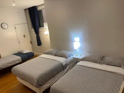 a room with three beds and a table with a clock at Hansem stay near Empire State Building in New York