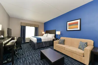 a hotel room with a bed and a couch and a desk at Holiday Inn Express & Suites Peekskill-Lower Hudson Valley by IHG in Peekskill