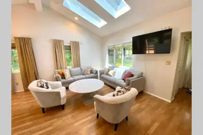 a living room with a couch and a table and chairs at Cozy 4BR 3BA Home- Train to NYC, USOpen, CitiField Mets, MSG, Walk to Harbor & Golf in Port Washington