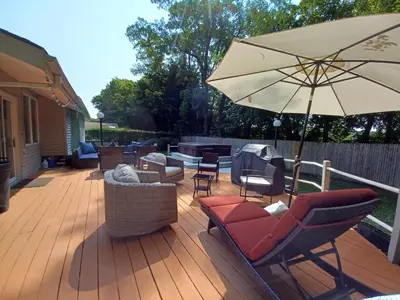 a patio with chairs and an umbrella on a deck at Cozy 4BR 3BA Home- Train to NYC, USOpen, CitiField Mets, MSG, Walk to Harbor & Golf in Port Washington