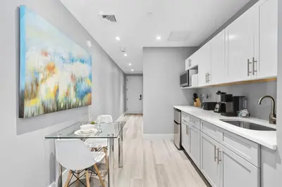 a kitchen with white cabinets and a painting on the wall at Global Luxury Suites at The Arches in Bronx