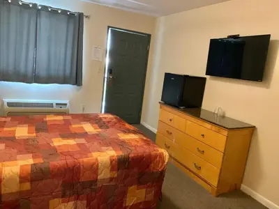 a bedroom with a bed and a dresser with a television at Nitey Nite Motel in South Windsor