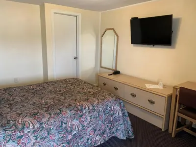a bedroom with a bed and a dresser with a television at Nitey Nite Motel in South Windsor