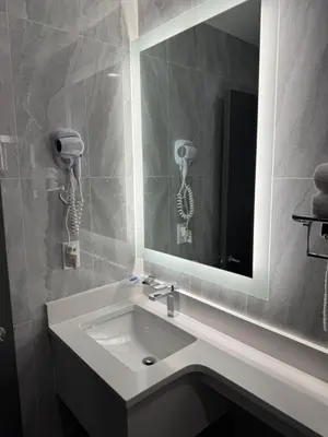 a bathroom with a sink with a mirror and a phone at Hotel The Villa - Long Island City in Queens