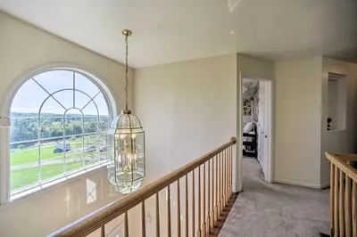 a staircase with a large window and a chandelier at Expansive Upstate Home with Home Theater! in East Schodack