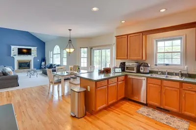 a kitchen with wooden cabinets and a living room at Expansive Upstate Home with Home Theater! in East Schodack