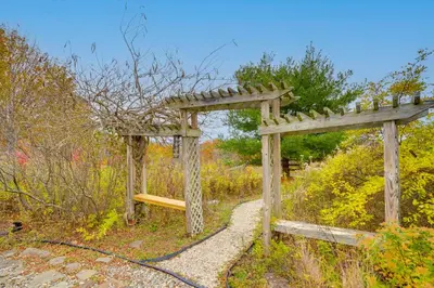 a wooden pergola with a bench on a trail at Expansive Upstate Home with Home Theater! in East Schodack