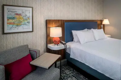 a hotel room with a bed and a chair at Hampton Inn & Suites Huntington Downtown, Ny in Huntington