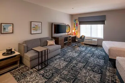 a hotel room with a bed and a couch and a television at Hampton Inn & Suites Huntington Downtown, Ny in Huntington