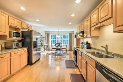 a kitchen with wooden cabinets and stainless steel appliances at Granby Home with Deck Less Than half Mi to Aldrich Lake! in Granby