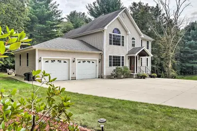 a white house with a garage with a driveway at Granby Home with Deck Less Than half Mi to Aldrich Lake! in Granby