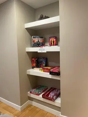 a book shelf filled with games and books at National at 888 Sixth Avenue - Furnished Apartments in New York