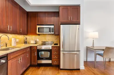 a kitchen with wooden cabinets and a stainless steel refrigerator at National at 888 Sixth Avenue - Furnished Apartments in New York