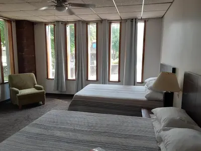 a bedroom with two beds and a chair and windows at Mountain View Lodge in Clifford