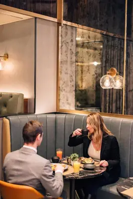 a man and woman sitting at a table in a restaurant at Hotel Indigo NYC Downtown - Wall Street by IHG in New York