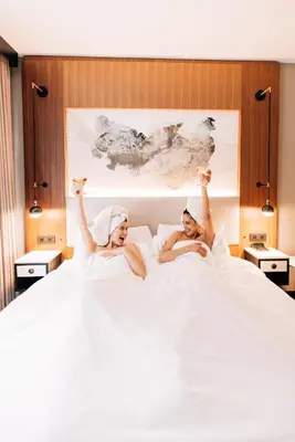 two women in towels laying in bed with their hands in the air at Hotel Indigo NYC Downtown - Wall Street by IHG in New York