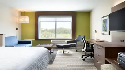 a hotel room with a bed and a desk and chairs at Holiday Inn Express - New Rochelle by IHG in New Rochelle