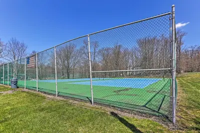a fence with a tennis court in a field at Deck and Backyard Tobyhanna Family Home in Tobyhanna