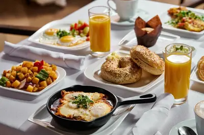 a table with plates of breakfast foods and orange juice at Sleepy Hollow Hotel in Tarrytown