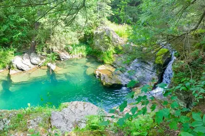 a river with blue water and rocks and trees at Waterfalls and Trails at The Mills At Green Hole in Hillsdale