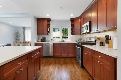 a large kitchen with wooden cabinets and white counter tops at New Stylish Beach Home near Stamford Downtown/Cove Beach/ 40 min to NYC in Stamford