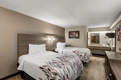 a hotel room with two beds and a television at Red Roof Inn Enfield in Enfield