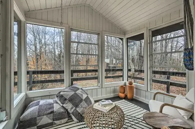 a room with windows and a couch and a table at Modern Hideaway with Deck and State Forest Access in Livingston Manor