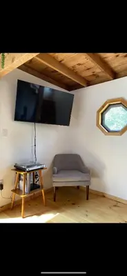 a room with a bench and a tv on a wall at The Cabin at Parkhill in Downsville