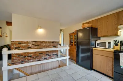 a kitchen with a black refrigerator and a brick wall at Dover Condo with Grill and Balcony 3 Mi to Mt Snow! in Dover