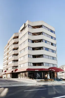 a tall white building with a restaurant in front of it at Stamford Suites in Stamford