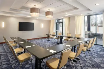 a conference room with tables and chairs and a flat screen tv at Courtyard by Marriott Saratoga Springs in Saratoga Springs