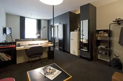a living room with a desk and a refrigerator at Ace Hotel New York in New York