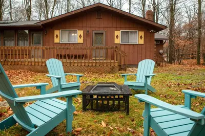 two blue chairs and a table in front of a house at Cozy Poconos Ranch Home with Pool Access, Near Lake! in Gouldsboro