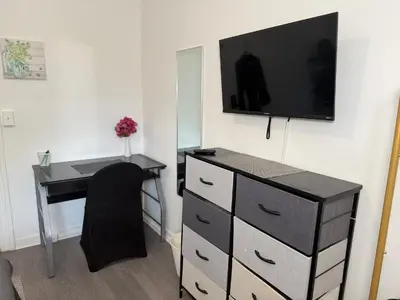 a desk with a tv on a wall and a desk with a chair at Modern Room in Shared Apartment Near NYC in Englewood
