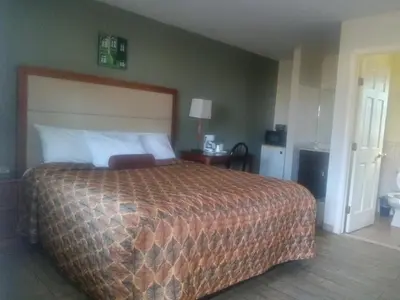 a bedroom with a large bed with a brown bedspread at Maple leaf motel in New Milford