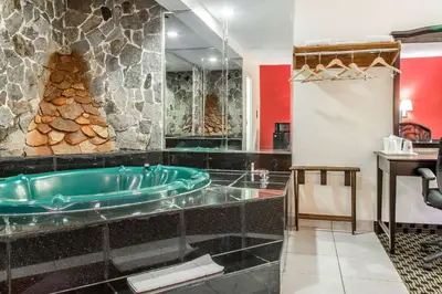 a bathroom with a tub and a stone wall at Econo Lodge in West Haven