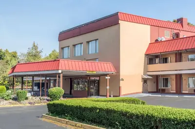a building with a red roof and a parking lot at Econo Lodge in West Haven