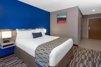 a hotel room with a large bed and a blue wall at Microtel Inn & Suites by Wyndham Bethel/Danbury in Bethel