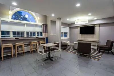 a waiting room with a table and chairs and a tv at Microtel Inn & Suites by Wyndham Bethel/Danbury in Bethel