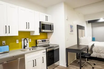 a kitchen with white cabinets and a sink and a bed at Peachtree Suites - Jersey City in Jersey City