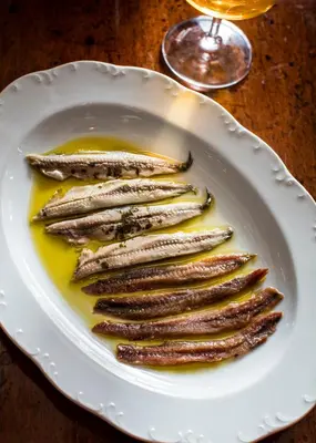 a white plate with a bunch of fish in a sauce at The Hotel Chelsea in New York