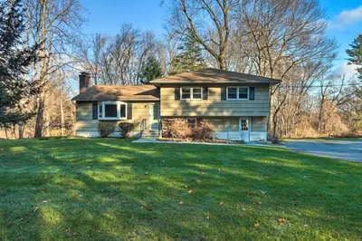 a house on a grassy hill with a yard at Family-Friendly Woodbury Home with Yard and Deck! in Woodbury