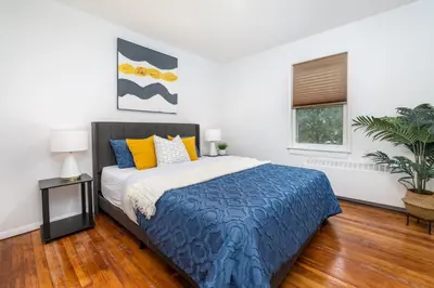 a bedroom with a bed with blue and yellow pillows at Lovely Ranch House in Windsor, 10 mins to Hartford Connecticut in Windsor