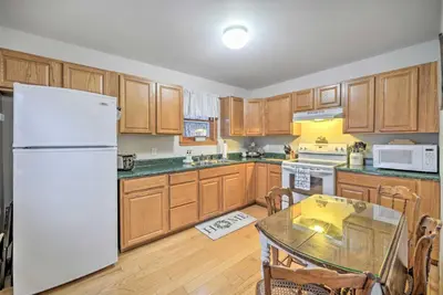 a kitchen with wooden cabinets and a white refrigerator at Lake Luzerne Home with Fire Pit on Hudson River in Lake Luzerne