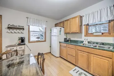 a kitchen with wooden cabinets and a white refrigerator at Lake Luzerne Home with Fire Pit on Hudson River in Lake Luzerne