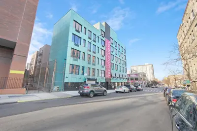 a building with cars parked on the side of a street at Hotel TREMONT Bronx Yankee Stadium in Bronx