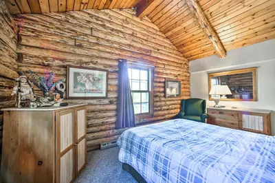 a bedroom with a bed and a wooden wall at Pet-Friendly New York Cabin with Hot Tub and Game Room in Maplecrest